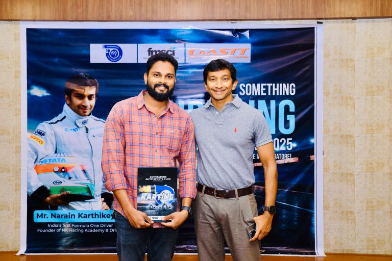 Two men pose together holding a booklet titled "KARTING" in front of a promotional backdrop featuring a racing theme.